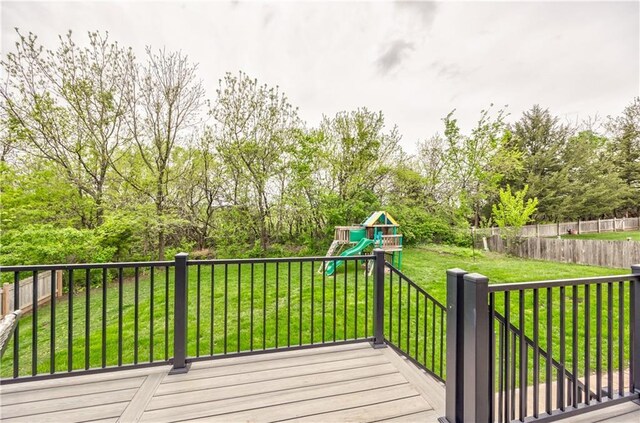 deck with a lawn, a fenced backyard, and a playground