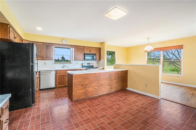 kitchen with baseboards, brown cabinetry, appliances with stainless steel finishes, and brick patterned floor