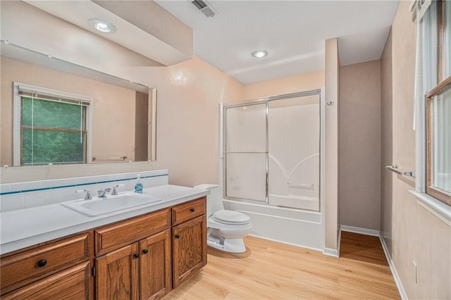 bathroom featuring shower / bath combination with glass door, vanity, toilet, wood finished floors, and visible vents