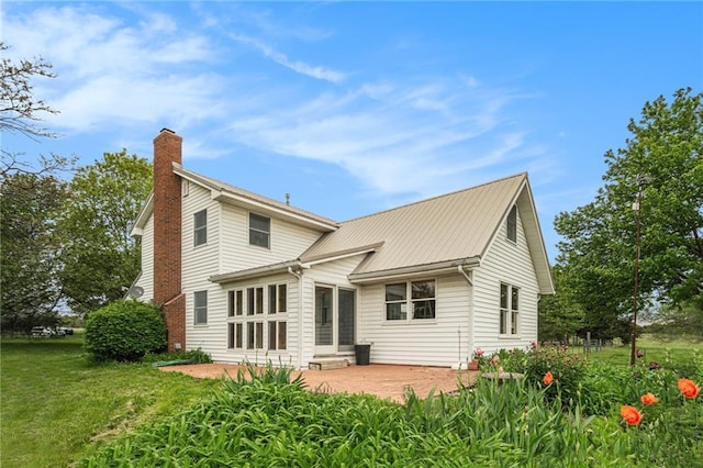 back of house with a patio area, a yard, and a chimney