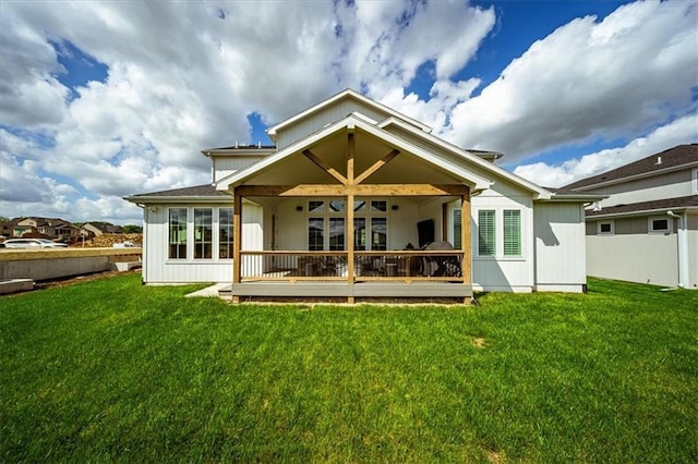 rear view of property featuring a lawn and fence