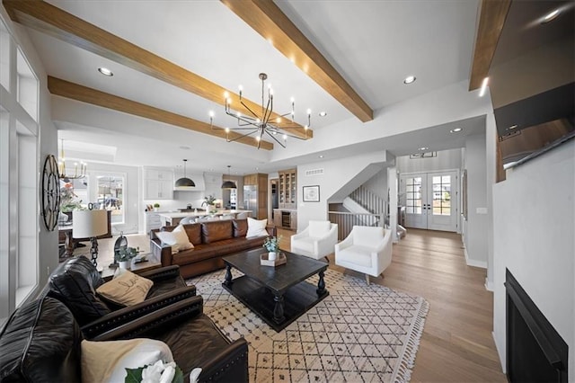 living room featuring an inviting chandelier, beamed ceiling, recessed lighting, french doors, and light wood finished floors