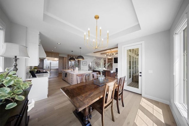 dining area featuring a raised ceiling, baseboards, a chandelier, recessed lighting, and light wood-style flooring