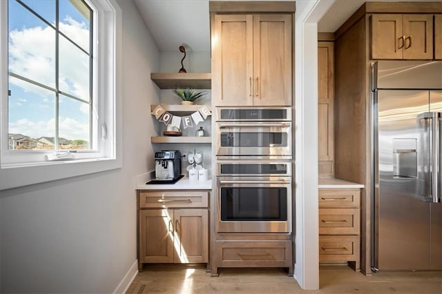 kitchen with light countertops, open shelves, appliances with stainless steel finishes, and light wood finished floors