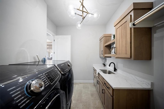 laundry room featuring cabinet space, an inviting chandelier, a sink, baseboards, and washer and clothes dryer