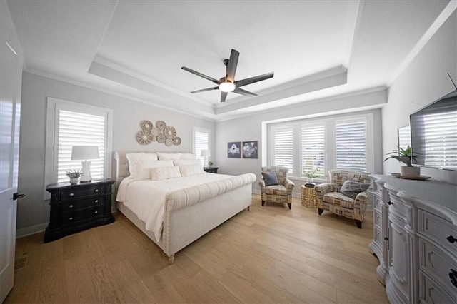 bedroom featuring crown molding, a raised ceiling, ceiling fan, and light wood-type flooring