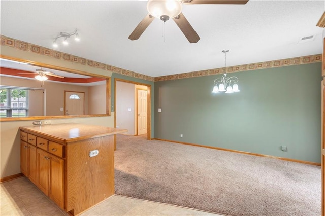 kitchen featuring visible vents, pendant lighting, open floor plan, light colored carpet, and ceiling fan with notable chandelier