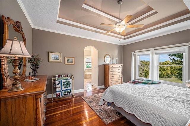 bedroom with arched walkways, a raised ceiling, wood finished floors, and ornamental molding