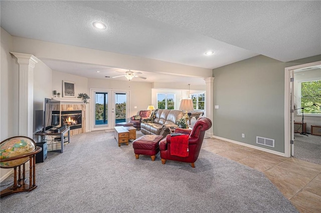 living room with a fireplace, carpet floors, a textured ceiling, ornate columns, and visible vents
