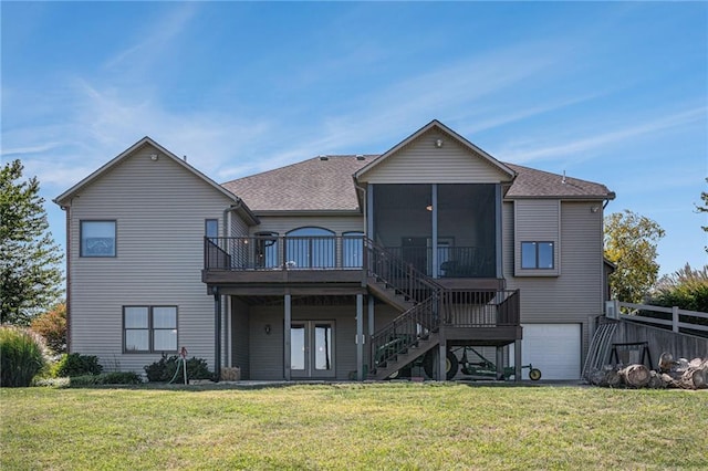 rear view of house featuring a garage, a wooden deck, stairs, a sunroom, and a lawn