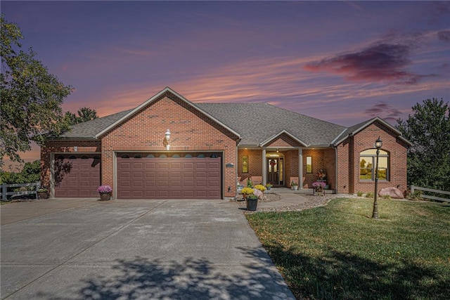 ranch-style house featuring brick siding, a garage, a front yard, and concrete driveway