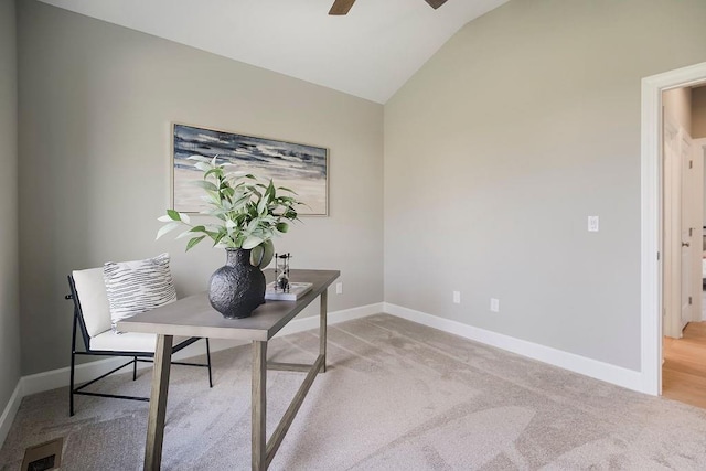 office area featuring a ceiling fan, light colored carpet, visible vents, baseboards, and lofted ceiling