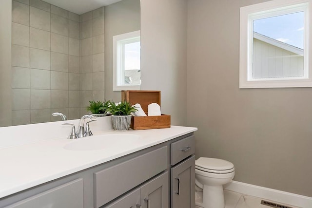 bathroom with vanity, baseboards, toilet, and a wealth of natural light