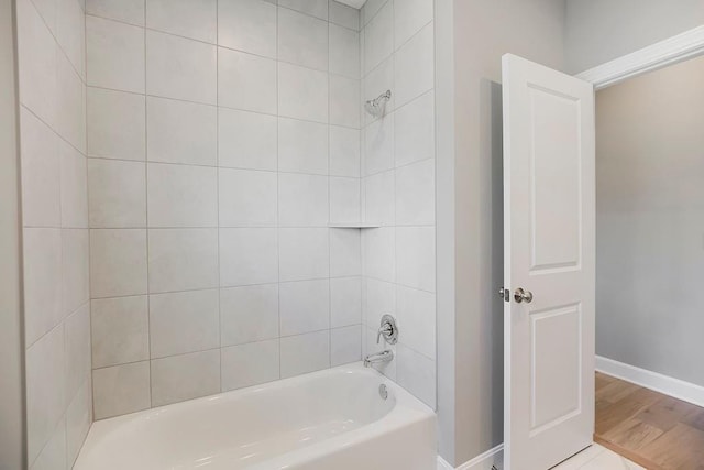 full bathroom featuring baseboards, washtub / shower combination, and wood finished floors