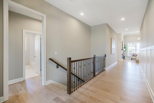 corridor featuring light wood-style floors, recessed lighting, baseboards, and an upstairs landing