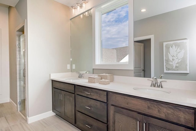 bathroom with double vanity, a sink, baseboards, and a shower stall