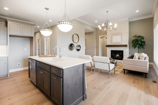 kitchen with a sink, light countertops, light wood-style flooring, stainless steel dishwasher, and ornamental molding