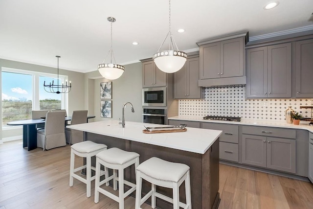 kitchen featuring light countertops, tasteful backsplash, light wood finished floors, gray cabinetry, and stainless steel appliances