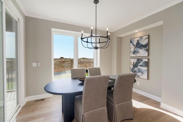 dining area featuring a notable chandelier, light wood-style floors, baseboards, visible vents, and ornamental molding