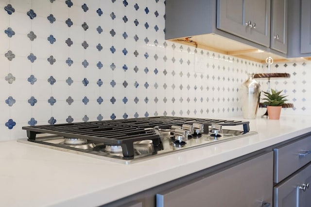 interior details featuring gray cabinetry, light countertops, tasteful backsplash, and stainless steel gas cooktop