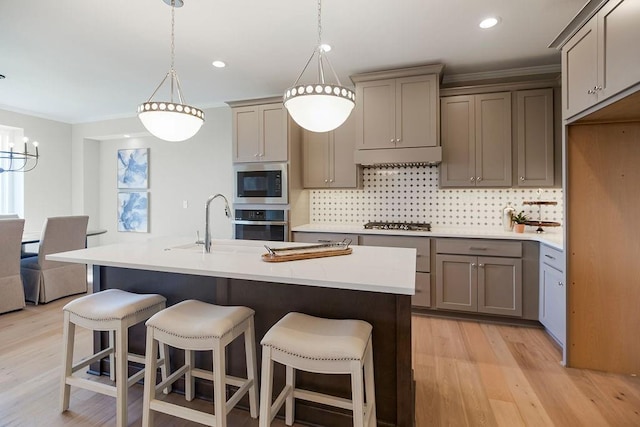 kitchen featuring gray cabinetry, tasteful backsplash, stainless steel appliances, and light wood-type flooring