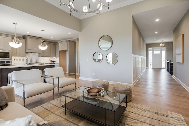 living area featuring an inviting chandelier, recessed lighting, light wood-style flooring, and baseboards