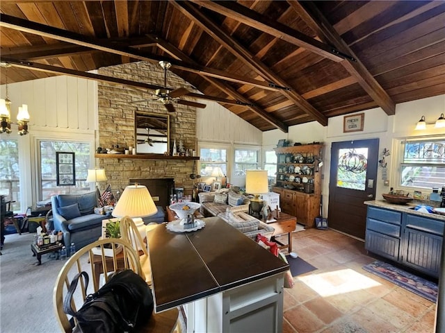 dining area featuring a stone fireplace, wooden ceiling, ceiling fan with notable chandelier, and high vaulted ceiling