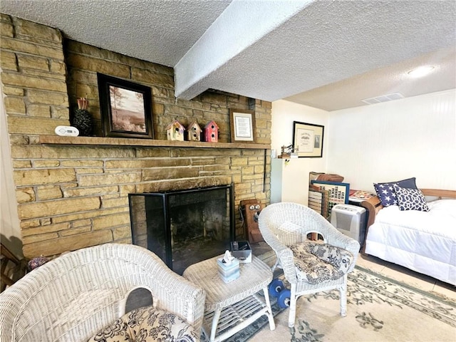 living room with a textured ceiling, visible vents, and a fireplace