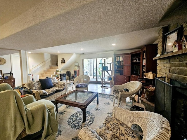 living area with recessed lighting, a textured ceiling, stairs, and a fireplace