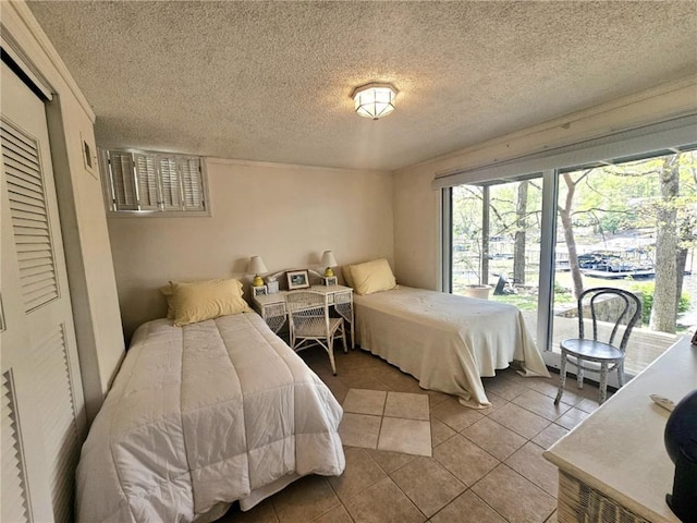 tiled bedroom featuring a textured ceiling and multiple windows