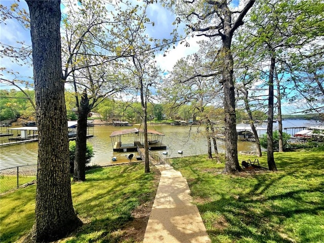 view of home's community with a water view, a yard, and a dock