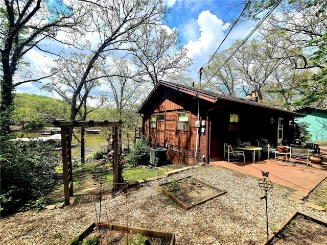 exterior space with central AC unit, a garden, and a chimney