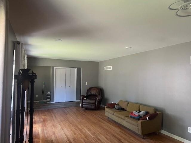 living room with baseboards, visible vents, and wood finished floors