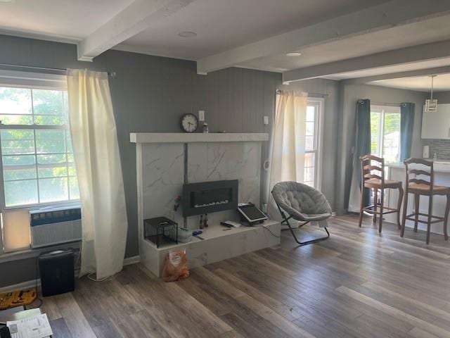 living room featuring cooling unit, beamed ceiling, wood finished floors, and a high end fireplace