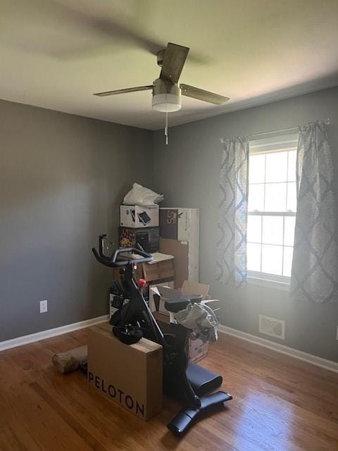 interior space with baseboards, ceiling fan, visible vents, and wood finished floors