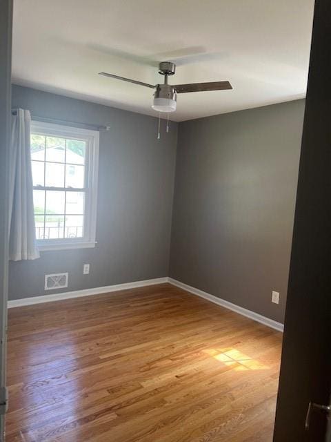 unfurnished room with a ceiling fan, baseboards, visible vents, and wood finished floors