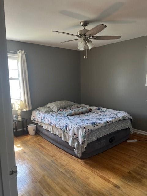 bedroom with baseboards, ceiling fan, and wood finished floors
