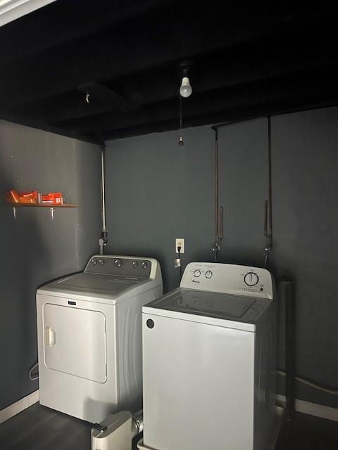 washroom featuring laundry area, baseboards, wood finished floors, and washing machine and clothes dryer