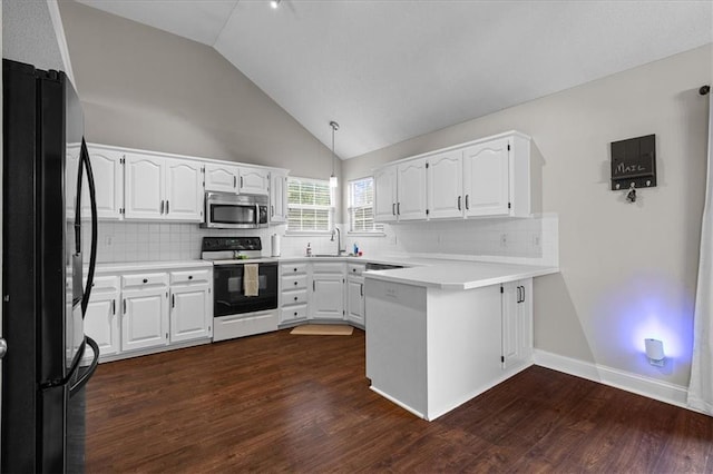 kitchen with freestanding refrigerator, electric range, a peninsula, stainless steel microwave, and a sink