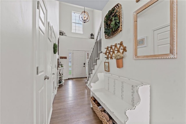 entrance foyer featuring an inviting chandelier, a towering ceiling, wood finished floors, and stairway