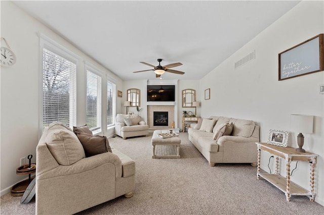 carpeted living area featuring a glass covered fireplace, ceiling fan, and visible vents