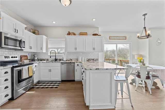 kitchen with a peninsula, a breakfast bar, a sink, appliances with stainless steel finishes, and a wealth of natural light