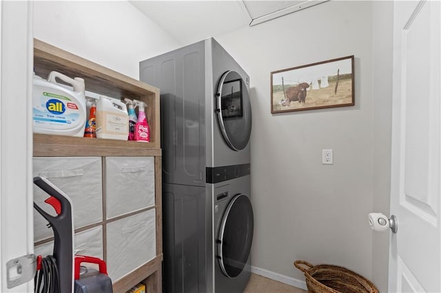 clothes washing area featuring laundry area, stacked washer / drying machine, and baseboards