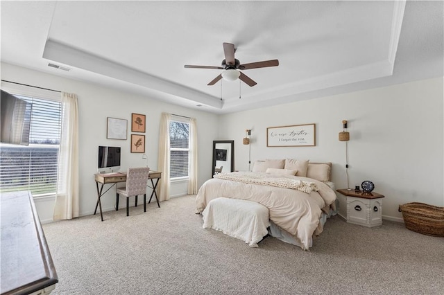 bedroom with carpet floors, visible vents, baseboards, a raised ceiling, and a ceiling fan
