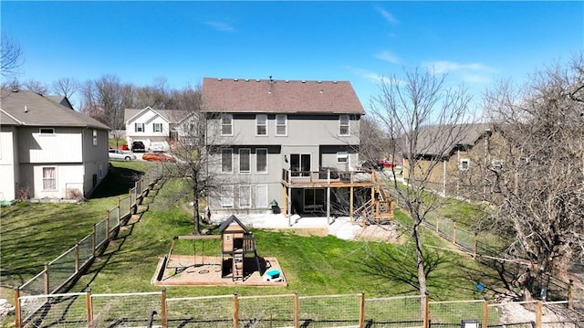 rear view of house featuring a lawn, a residential view, a fenced backyard, a playground, and stucco siding
