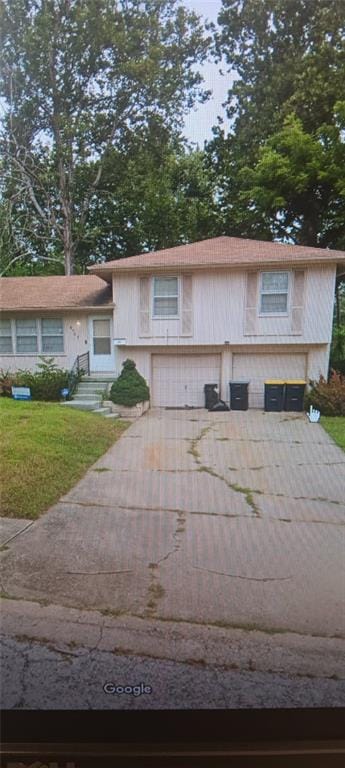 tri-level home featuring a garage, entry steps, driveway, and a front lawn