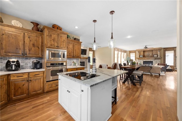 9924 Skyview Ln, Lenexa, KS 66220 - kitchen with appliances with stainless steel finishes, a fireplace, tasteful backsplash, a breakfast bar area, and recessed lighting