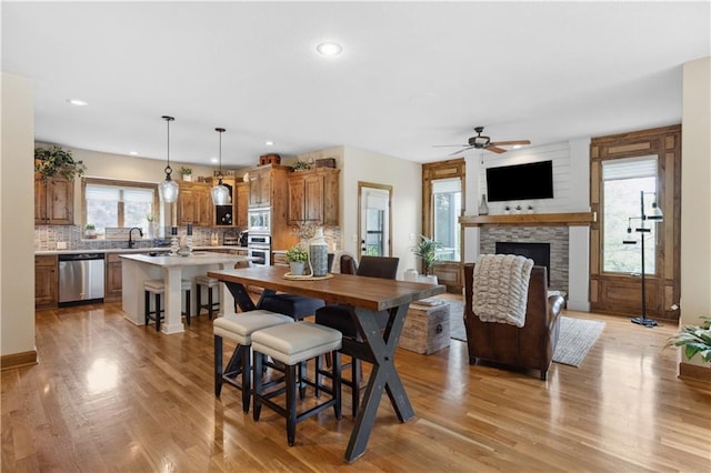 9924 Skyview Ln, Lenexa, KS 66220 - dining space with light wood-style floors, a stone fireplace, a ceiling fan, and recessed lighting