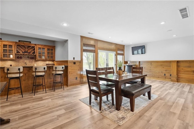 9924 Skyview Ln, Lenexa, KS 66220 - dining space featuring wainscoting, light wood finished floors, recessed lighting, bar area, and wooden walls