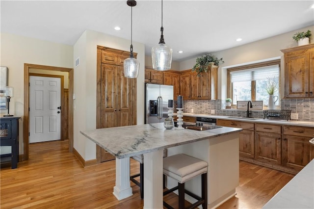 9924 Skyview Ln, Lenexa, KS 66220 - kitchen with stainless steel fridge, light wood finished floors, backsplash, a breakfast bar area, and recessed lighting
